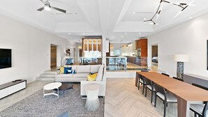 A modern living room with a sofa, coffee table, and dining area with chairs. - Ocean Terraces Penthouse 3BR (Nassau)