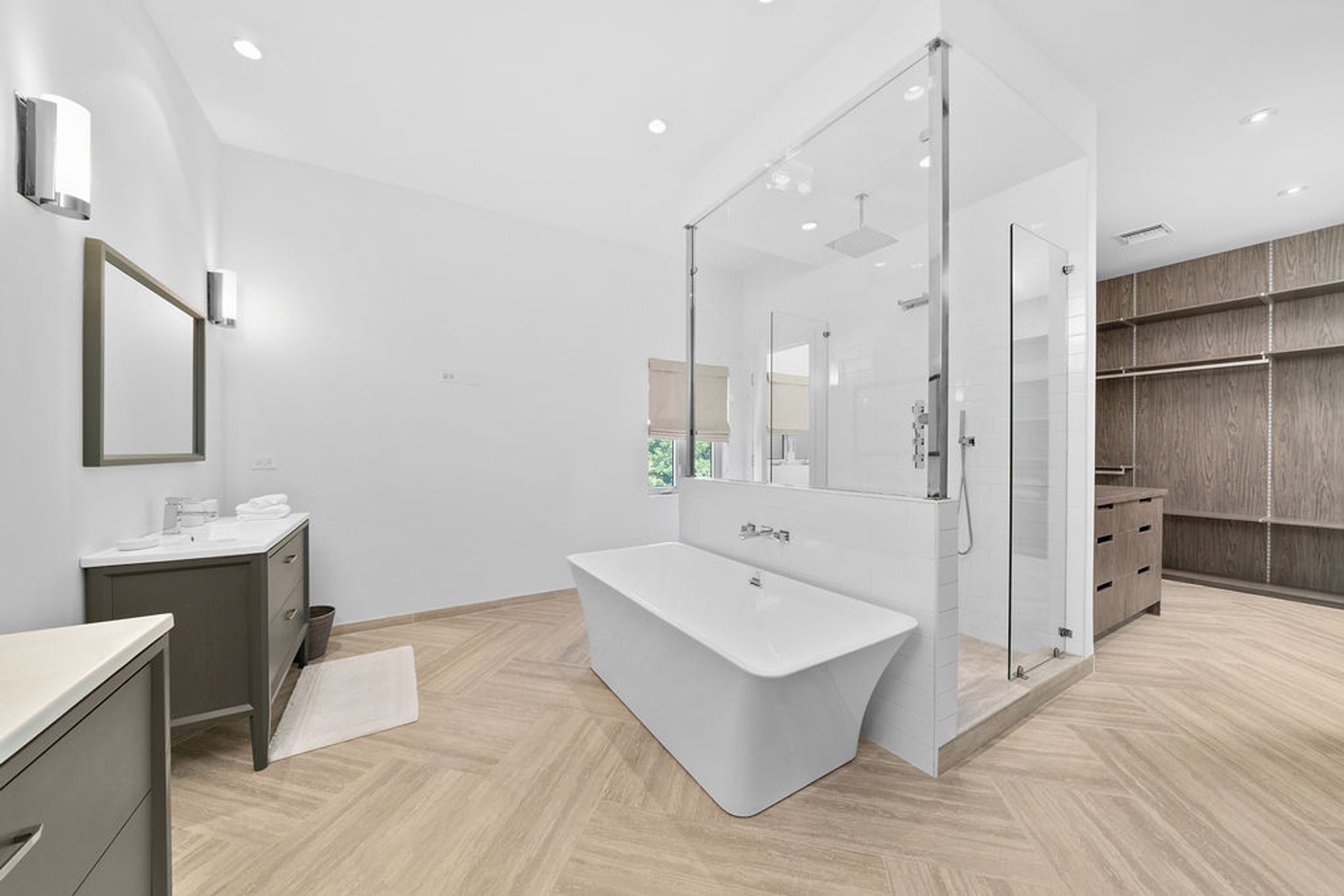 A modern bathroom with a freestanding bathtub, a vanity with a mirror, and a walk-in shower.