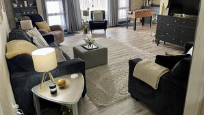 A modern living room with a sofa, armchair, coffee table, and a foosball table. - The Split Rock ~ CLEAN, Safe, Convenient Location (Bismarck)