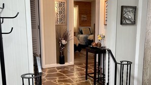 A stone-floored entrance with a staircase, a decorative wall piece, and a hanging light fixture. - The Split Rock ~ CLEAN, Safe, Convenient Location (Bismarck)