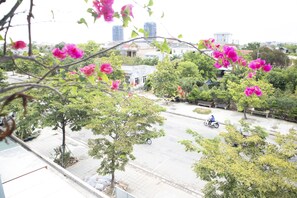 A street view with trees, a motorbike, and buildings in the background. - Memory Homestay (Hue)