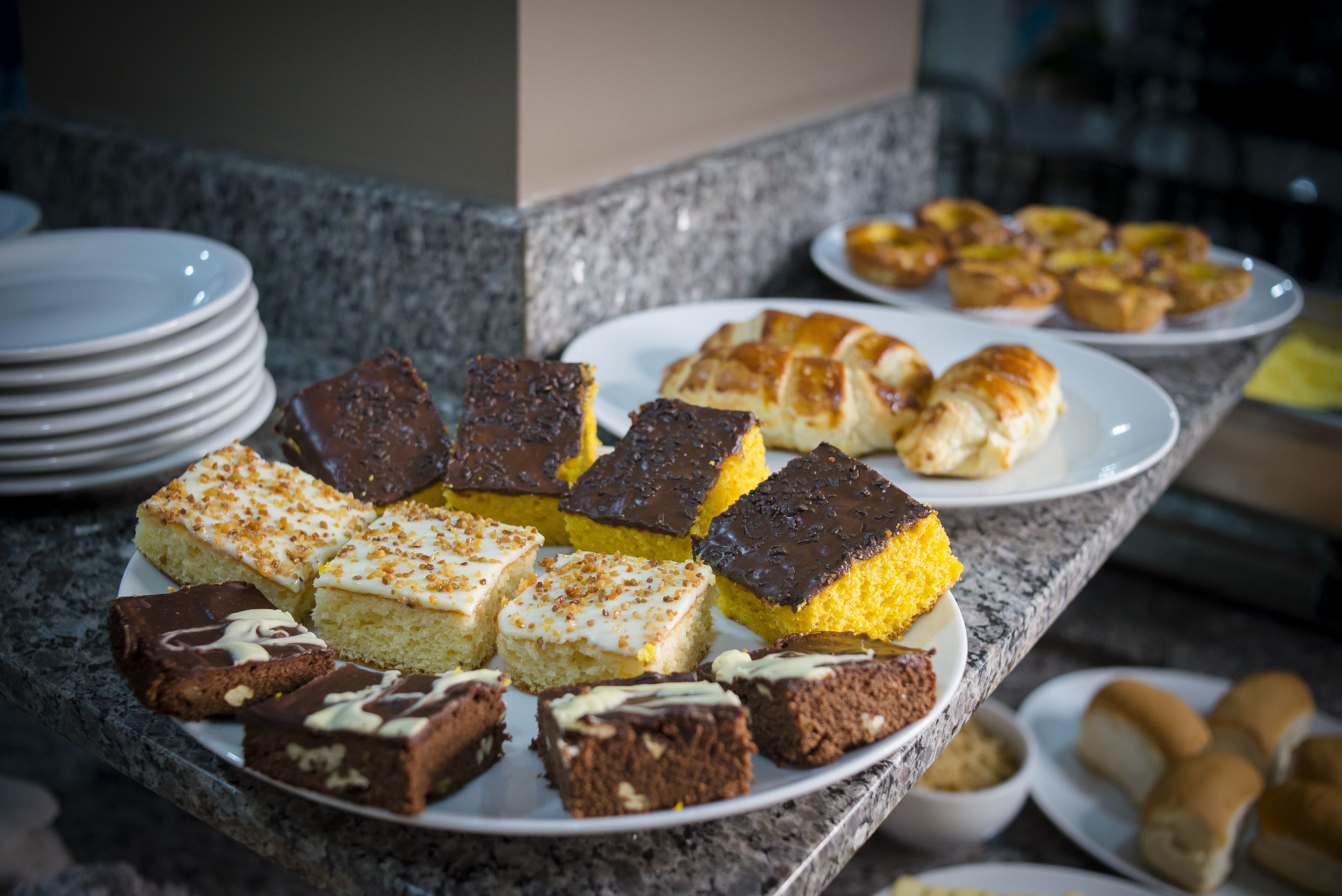 A buffet table with various desserts including brownies, cakes, and pastries.