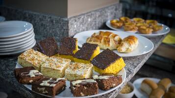 A buffet table with various desserts including brownies, cakes, and pastries.