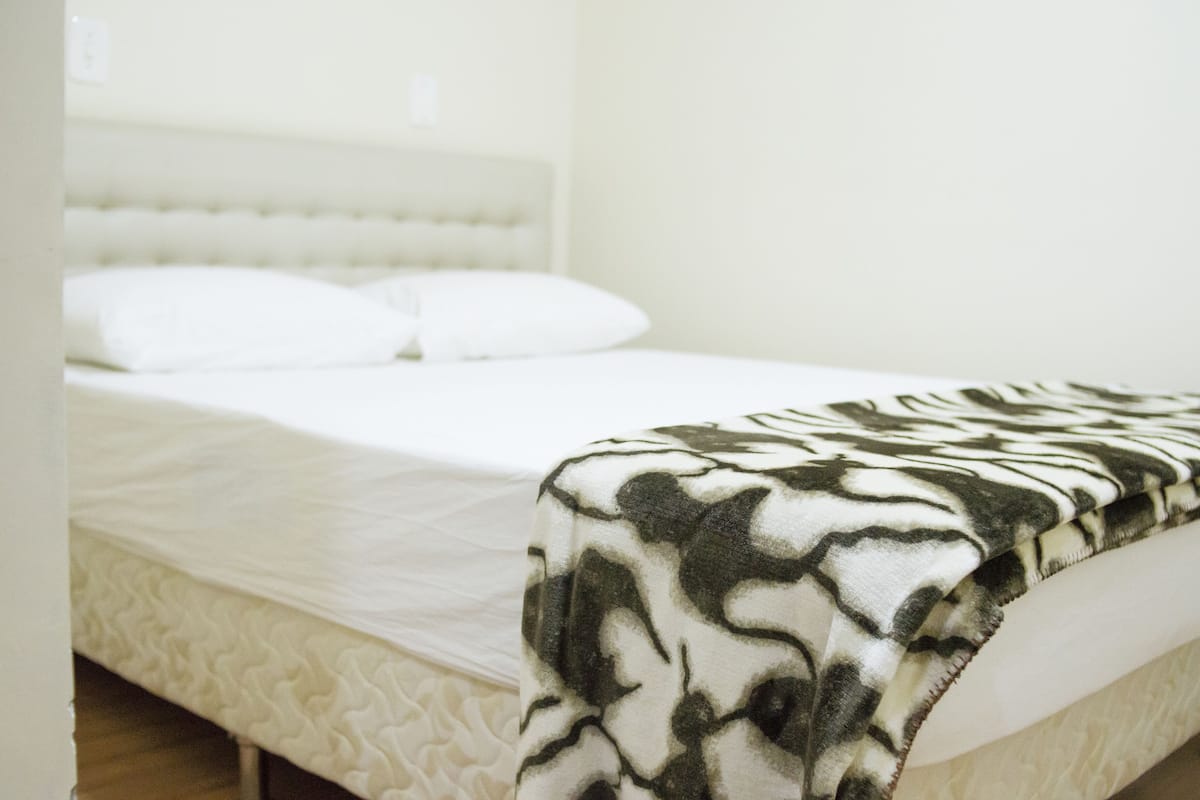A bed with a patterned blanket and a headboard.
