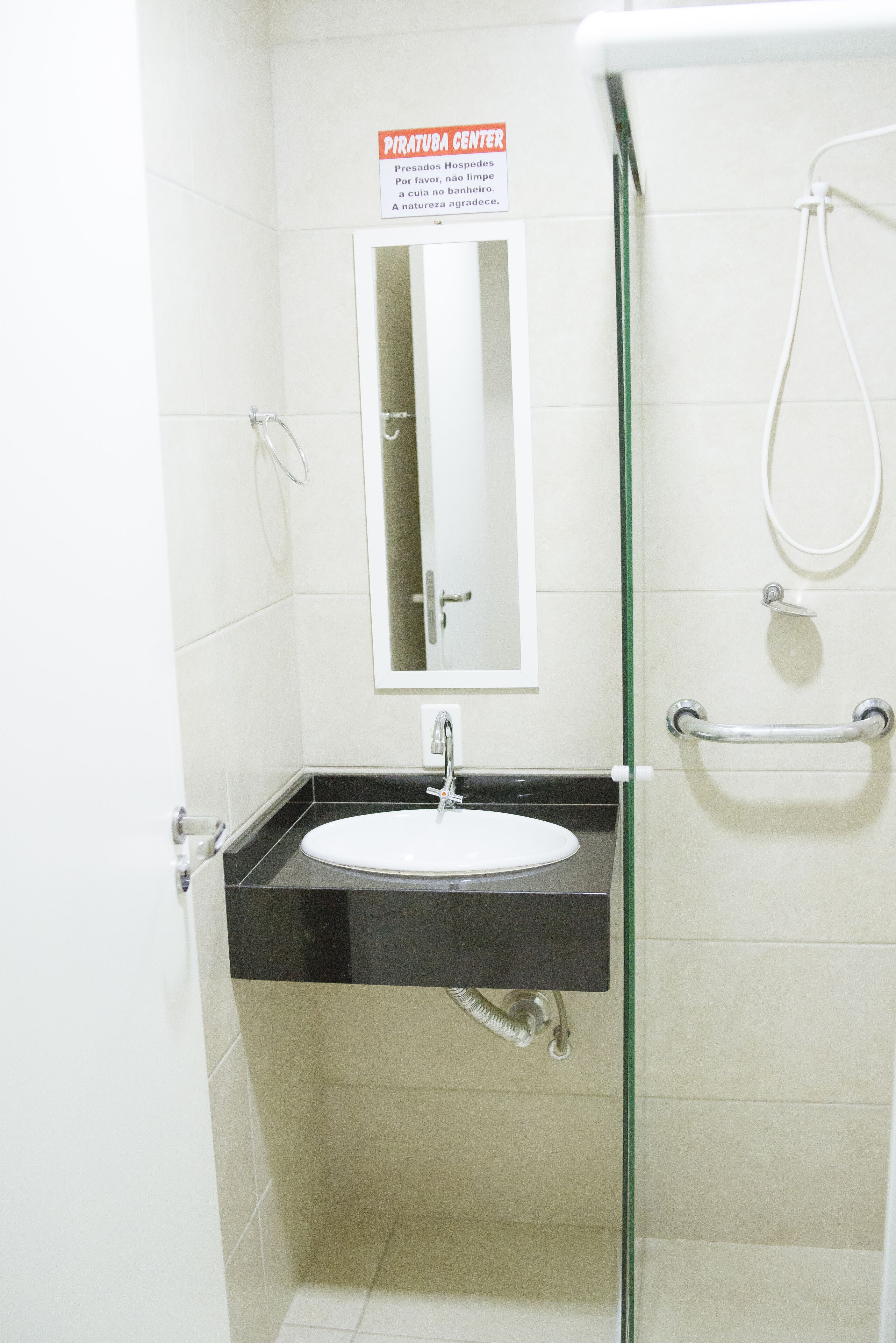 Une petite salle de bain avec un lavabo blanc, un miroir et une douche.
