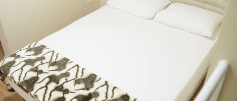 A bed with a patterned blanket, a tufted headboard, and white pillows.