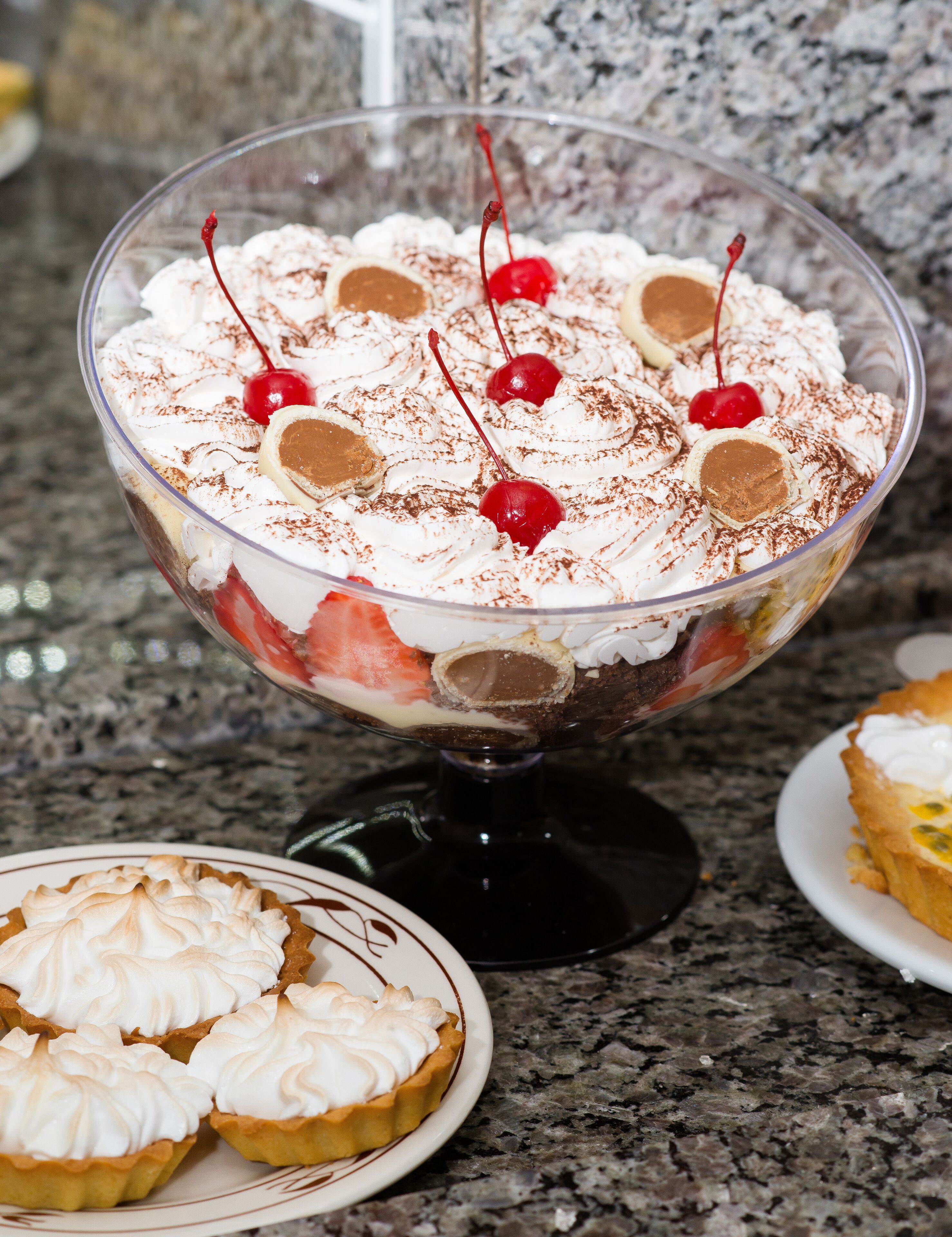 A dessert in a clear glass bowl on a granite countertop.