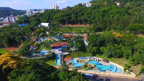 Un resort con múltiples piscinas, un tobogán acuático grande y abundante vegetación alrededor de las instalaciones.