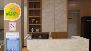 Un mostrador de recepción de hotel con encimera de mármol, estanterías de madera con objetos decorativos y un cartel que indica la salida.