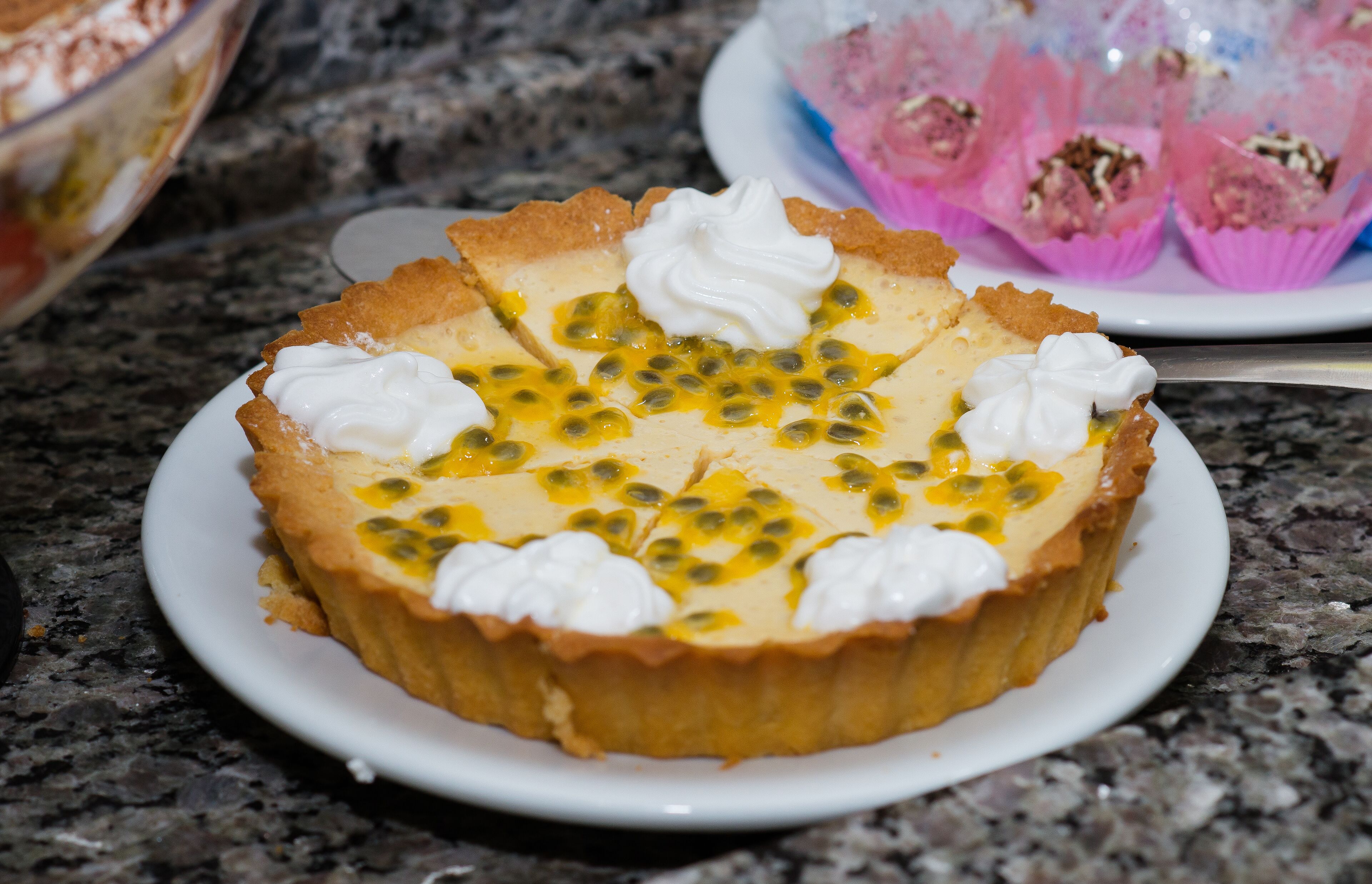 A pie with whipped cream and passion fruit on a plate.