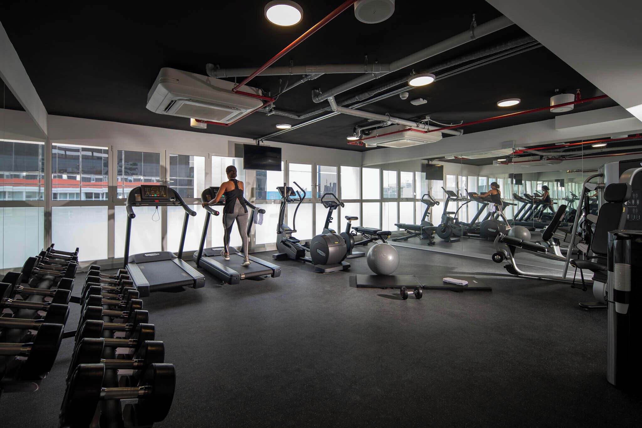 Un gimnasio con cintas de correr, mancuernas y pelotas de ejercicio.