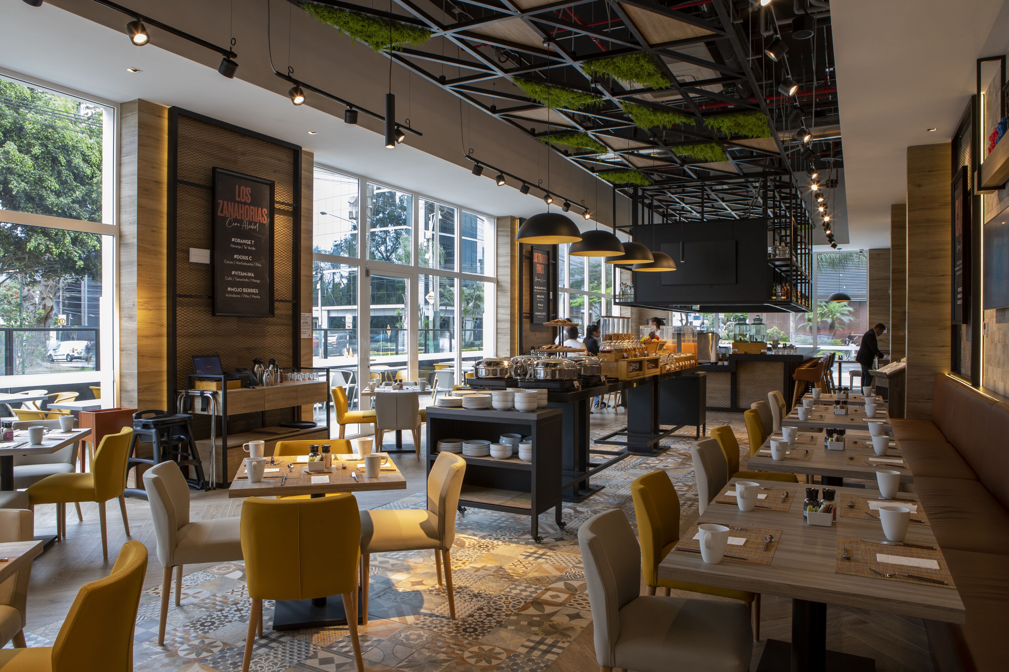 Un restaurante moderno con una barra larga, sillas amarillas y una zona de bar.