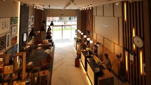 Een moderne hotel lobby met een receptiebalie, een zithoek en een grote klok aan de muur.