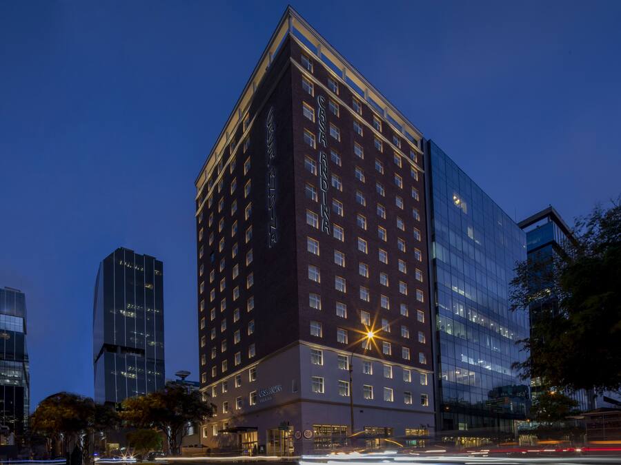 A modern hotel with a glass facade, multiple floors, and a prominent entrance.