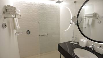 Een moderne badkamer met een douchecabine van glas, een zwart wastafel en een grote spiegel.
