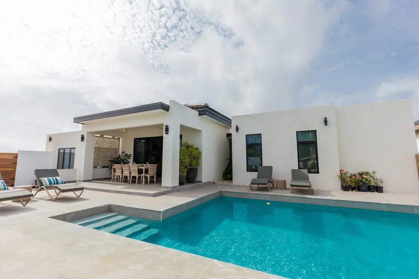 A modern house with a swimming pool, outdoor seating, and a patio area.