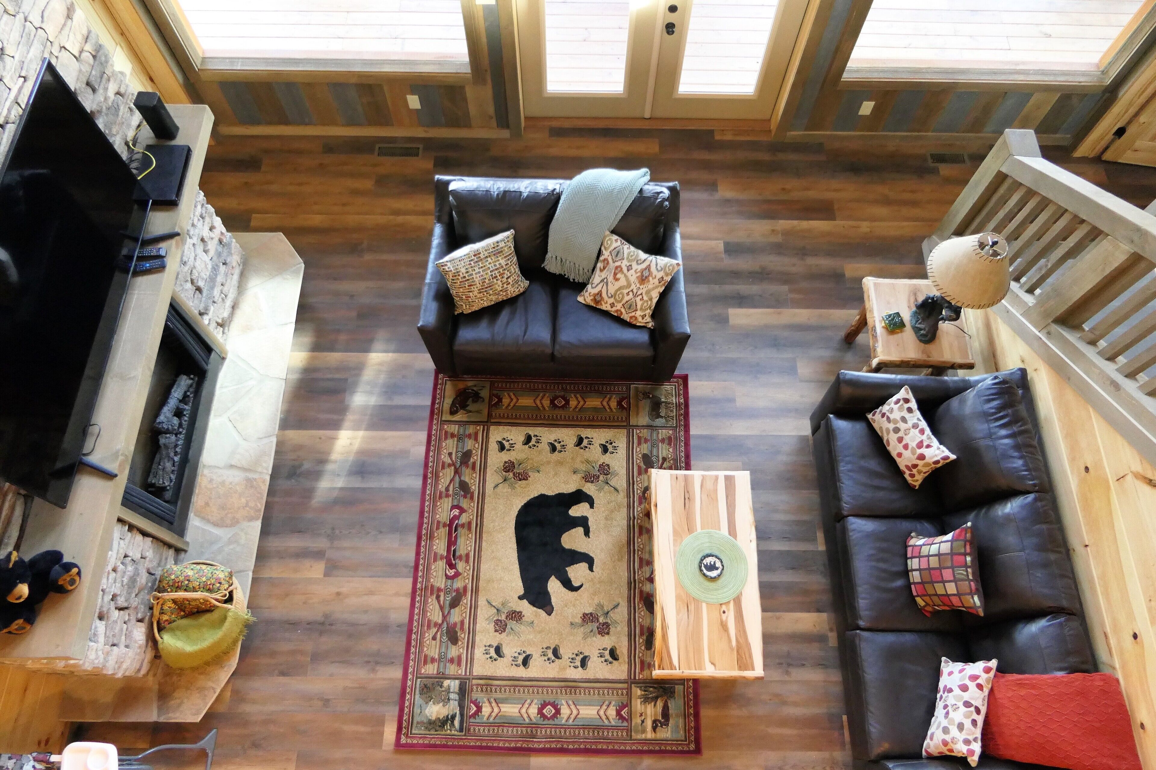 A cozy living room with a fireplace, a brown leather sofa, and a patterned rug.
