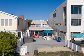 A residential building with a patio area featuring outdoor seating and umbrellas.