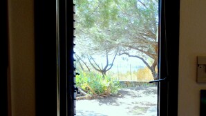 A window with a view of a tree and a stone wall. - Villa dell'Arte, on the beach of Porto Sa Ruxi, Villasimius (Porto Sa Ruxi)
