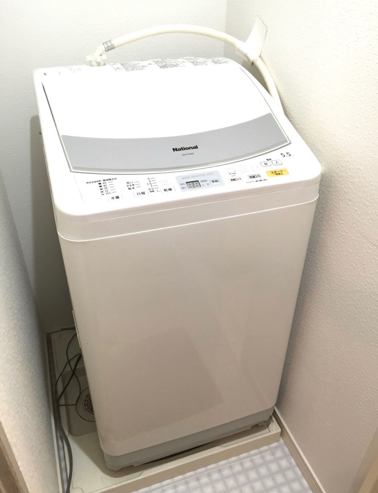 A white National brand washing machine with a control panel and a water inlet hose.