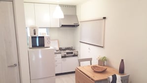 Uma cozinha compacta com eletrodomésticos brancos, uma mesa de jantar de madeira e um lustre.