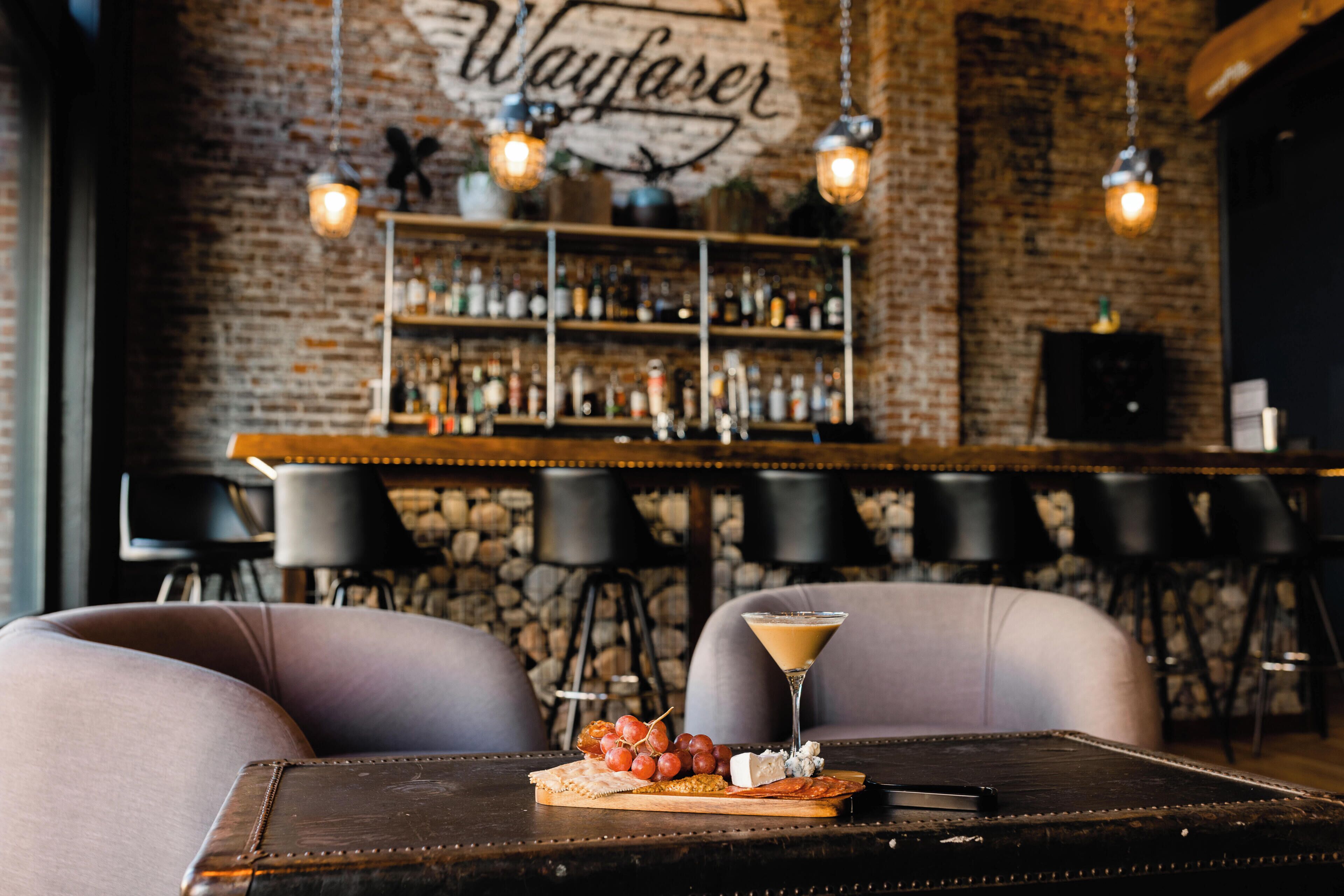A bar area with a stone wall, hanging lights, and a bar counter.