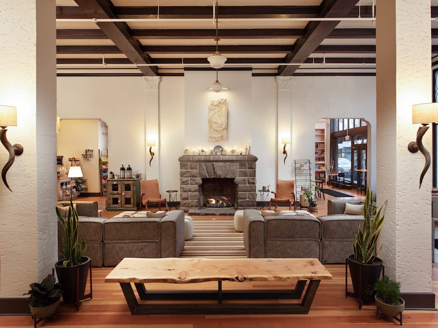 A spacious lobby with a stone fireplace, comfortable seating, and a large wooden table.