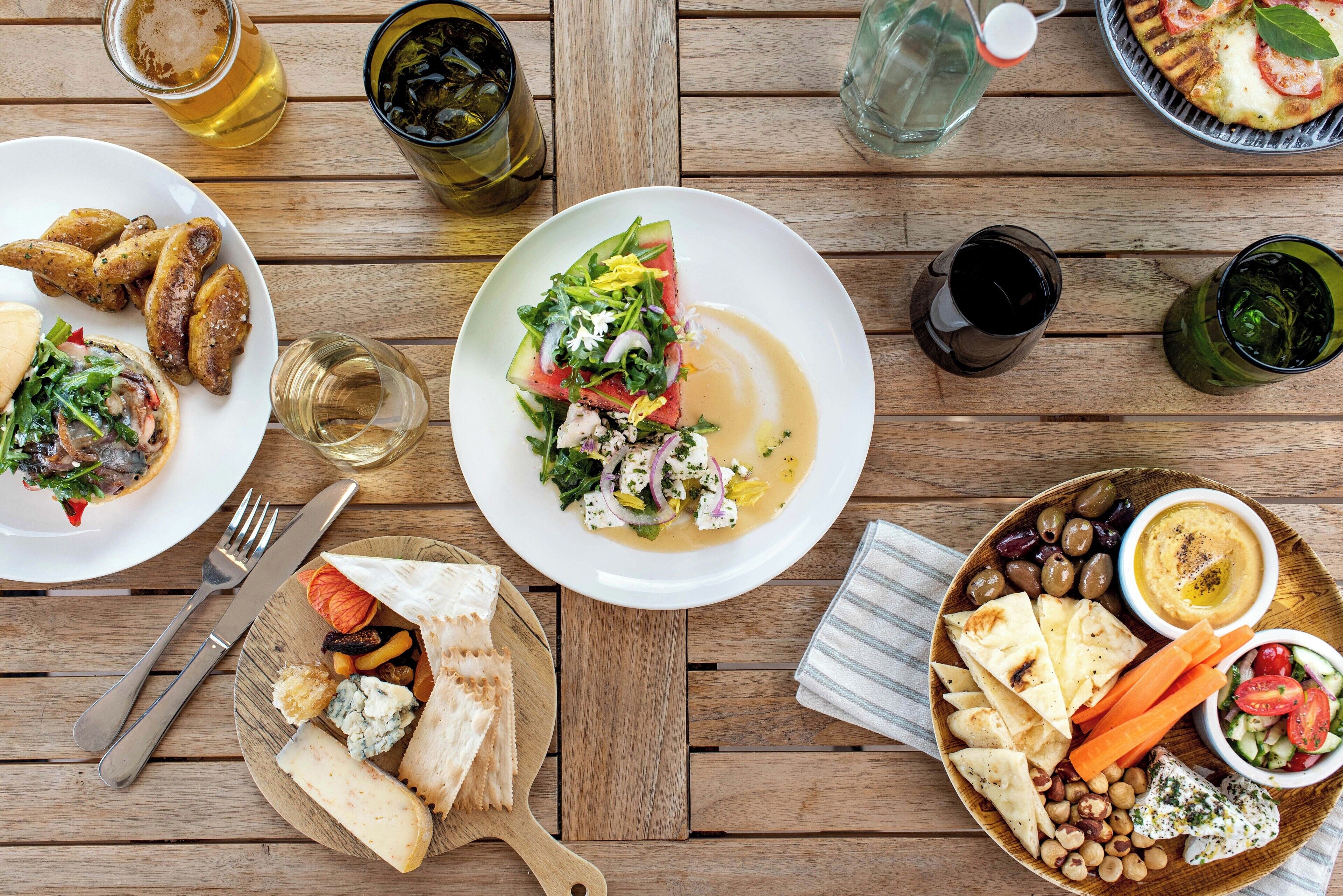 A wooden table with various dishes, drinks, and cutlery.