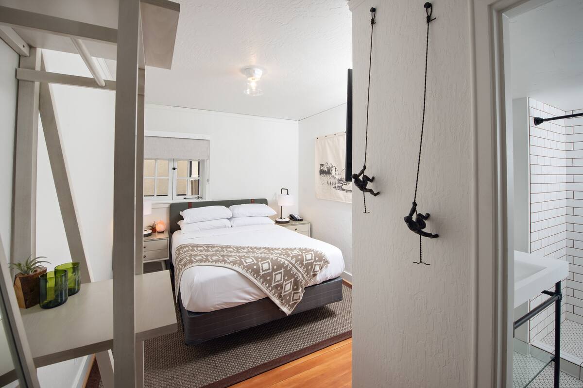 A modern bedroom with a bed, bedside table, lamp, and a hanging monkey decoration.