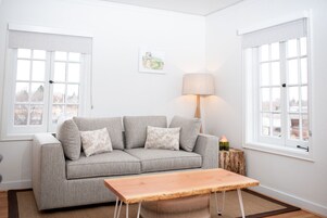 A living room with a grey sofa, a wooden coffee table, a lamp, and a framed picture on the wall.