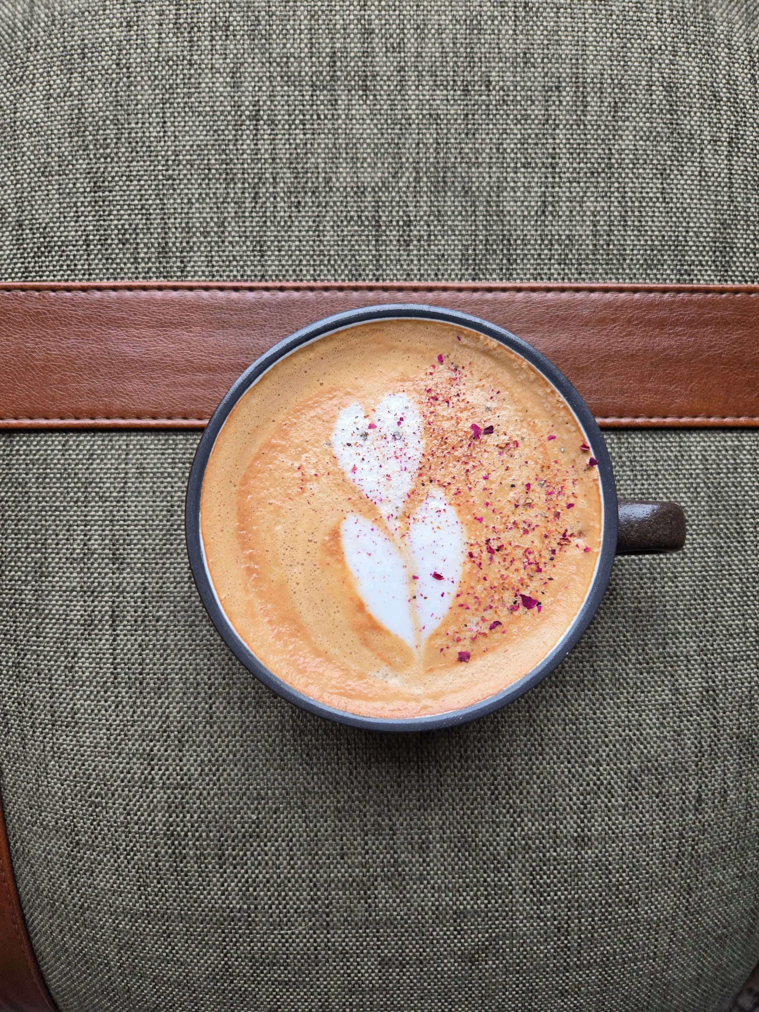 Une tasse de café ornée d’un motif en latte art, posée sur une surface texturée.