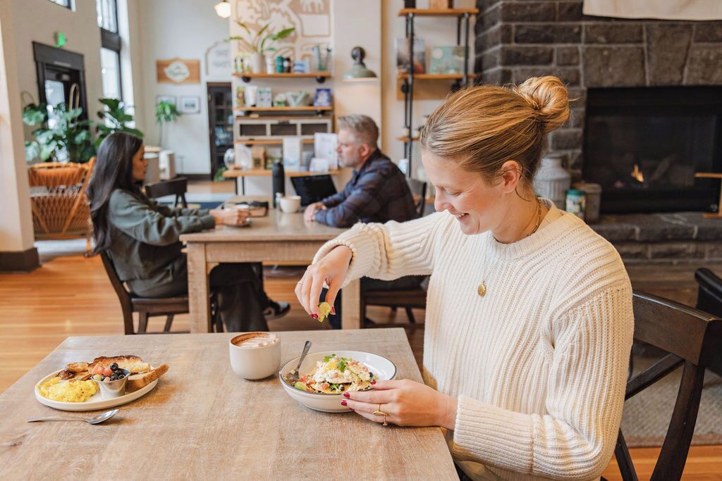 A cozy dining area with a fireplace, wooden furniture, and a variety of dishes on the table.