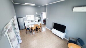 A modern kitchen with a dining area, a flat-screen TV, and a small seating area. - Ulsan Ganjeolgot View Pension (Ulsan)