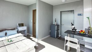 A bedroom with a bed, bedside table, and a small desk with a chair. - Ulsan Ganjeolgot View Pension (Ulsan)