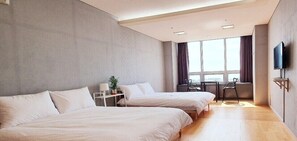 A modern hotel room with two beds, a desk, a chair, a TV, and a large window with curtains. - Treehouse (Incheon)