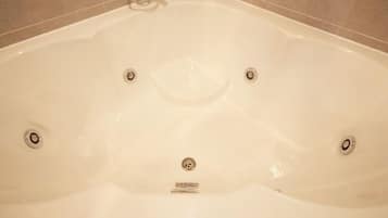 A bathtub with four faucets and a drain.