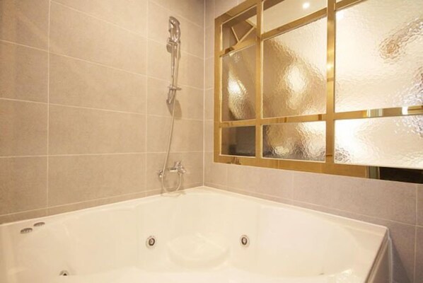 A bathroom with a large bathtub, a glass shower enclosure, and a frosted glass window.