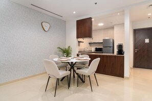 A modern kitchen with a microwave, refrigerator, and coffee maker. There is a dining area with a round table and four chairs.