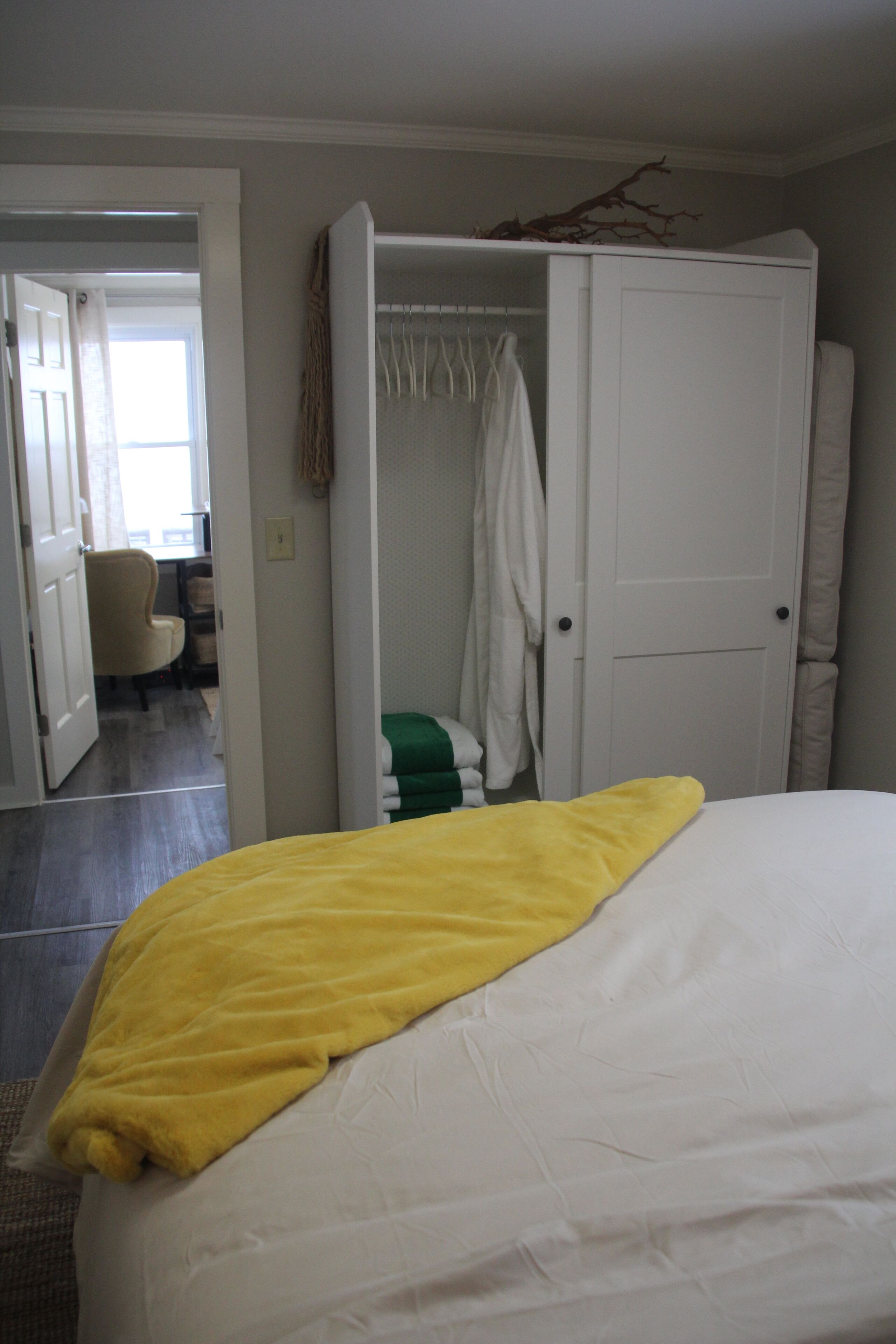 Ein Schlafzimmer mit einem Bett, einem Kleiderschrank und einem Stuhl im Hintergrund.