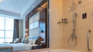 Ein modernes Badezimmer mit einer großen Badewanne, einer Dusche und einem Fenster mit Glasverkleidung.