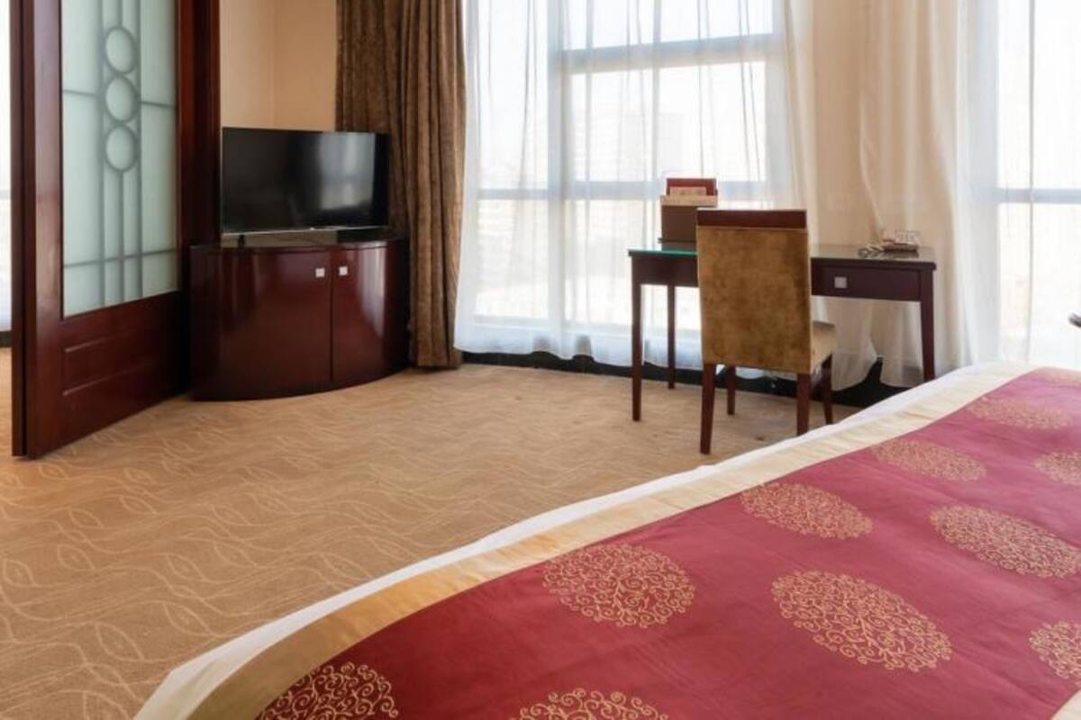 Ein Hotelzimmer mit Bett, Fernseher, Schreibtisch und Stuhl.
