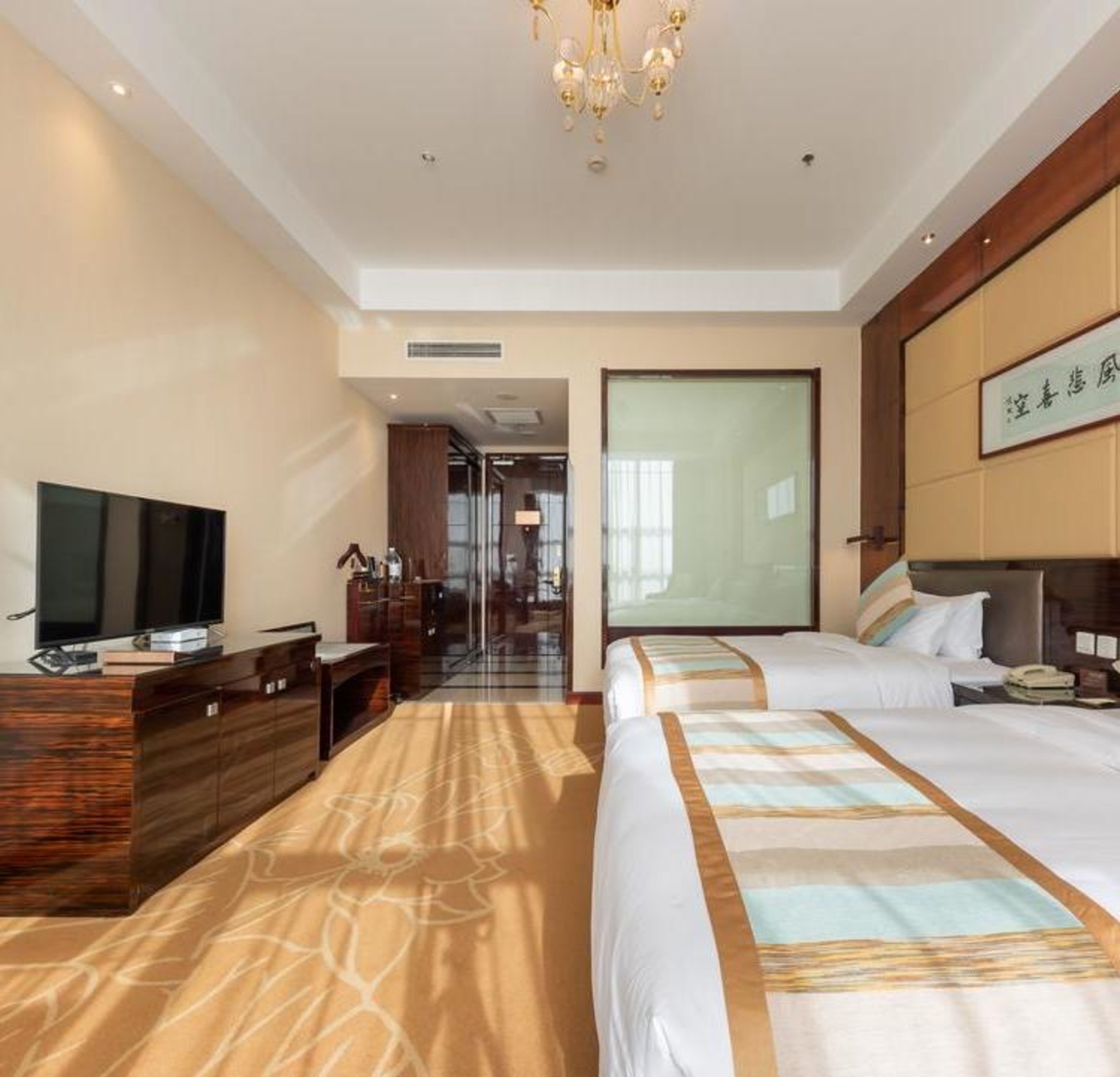 Une chambre d’hôtel avec deux lits, une télévision, un bureau et une grande fenêtre.