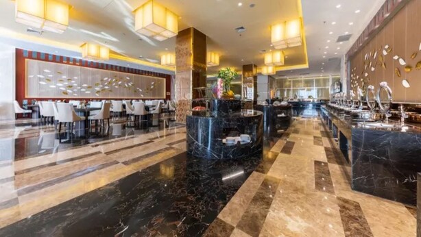 Eine geräumige Lobby mit Schachbrettmuster-Boden, Marmor-Theken und modernen Leuchten.