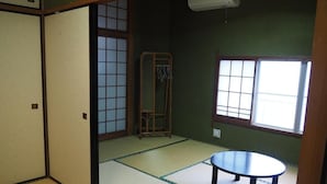 Una habitación japonesa tradicional con suelo de tatami, una puerta corredera shoji, una mesa baja de tatami y un perchero.