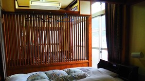 Un dormitorio con cabecera de madera, cama con ropa de cama floral y una ventana con cortinas.