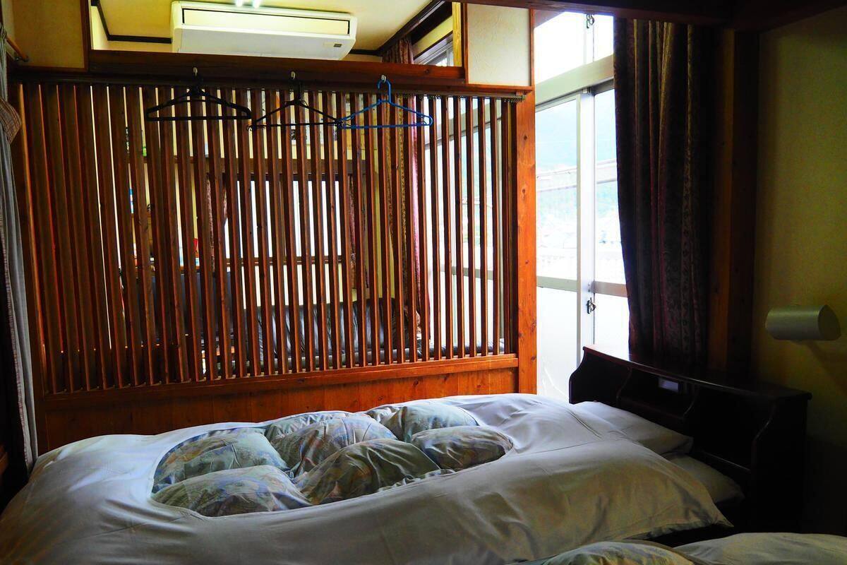 Een slaapkamer met een houten hoofdeinde, een bed met bloemenbeddengoed en een raam met gordijnen.