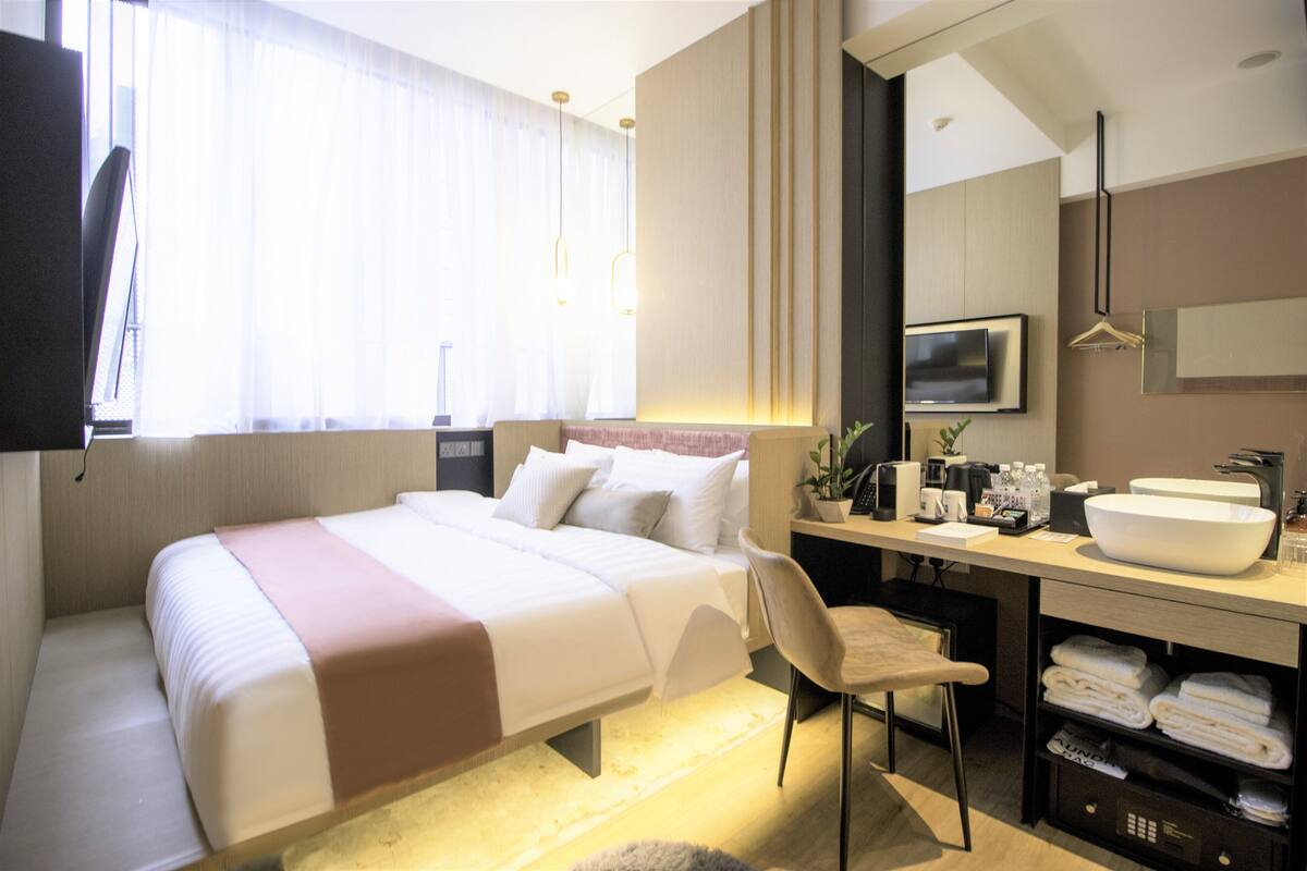 Une chambre d’hôtel avec un grand lit, un bureau doté d’un lavabo et une chaise.