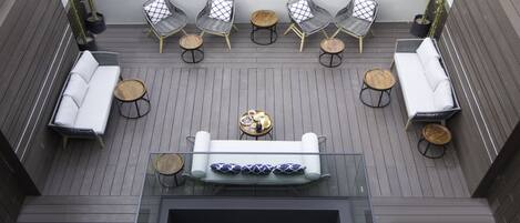Eine Dachterrasse mit einer zentralen Sitzgruppe, umgeben von vier Stühlen und zwei Sofas, und einem kleinen runden Tisch in der Mitte.