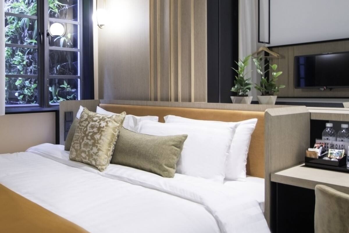 Une chambre d’hôtel équipée d’un lit, d’une télévision, d’un bureau avec une machine à café et d’une fenêtre avec des rideaux.