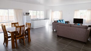 A spacious living area with a dining table, chairs, a sofa, and a TV. - Charlie's Villas (Rarotonga)